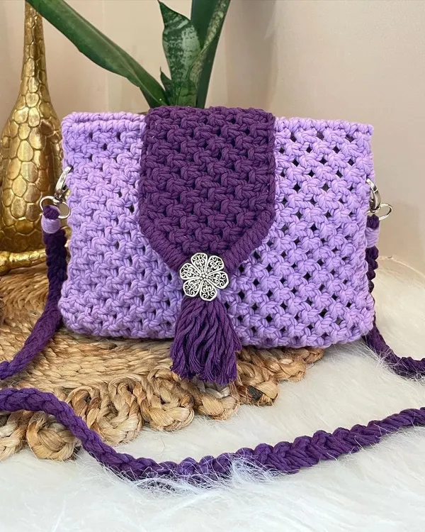Embrace the magic of purple with this enchanting sling bag. It features a dark purple flap with a decorative metal flower and tassel, set against a lighter lavender body for a beautiful two-tone effect.