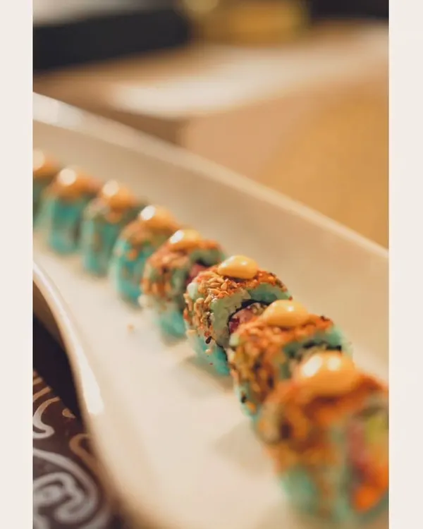 Sushi, because it’s cheaper than therapy. A beautiful platter of our signature sushi rolls, featuring colorful ingredients and a creamy topping.