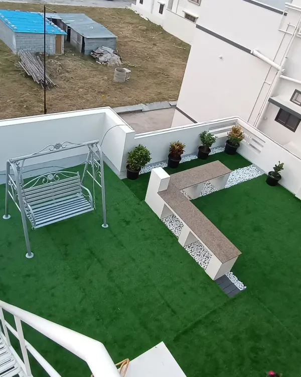 This high-angle shot captures the full scope of a rooftop garden I designed and installed. It features a large artificial lawn, a garden swing, and a built-in seating area.