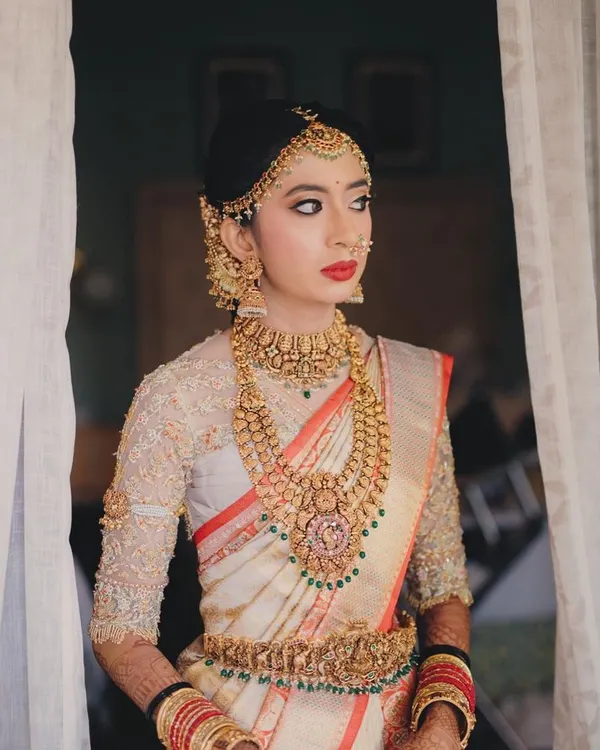 A picture of pure elegance. This bride's look features a classic red lip, a sharp wing, and a traditional matha patti, creating a timeless portrait for her wedding day.
