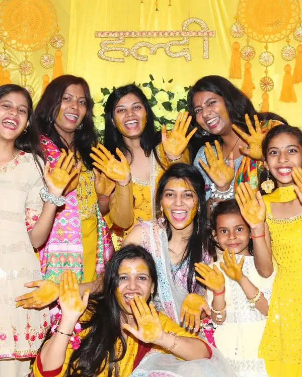 This is the energy I love to capture. A candid group shot from a Haldi ceremony, where everyone is laughing and showing their turmeric-covered hands against a vibrant yellow backdrop. It’s all about freezing these moments of pure joy.
