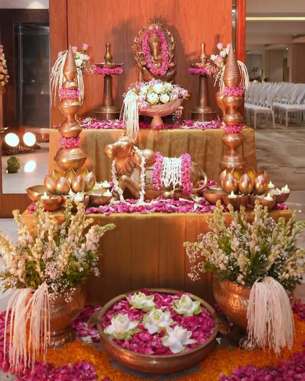 A complete Ganpati puja setup I designed. It features a central altar with the idol, flanked by traditional brass lamps and vessels, a Nandi statue, and an abundance of fresh flowers and petals, creating a truly divine space.