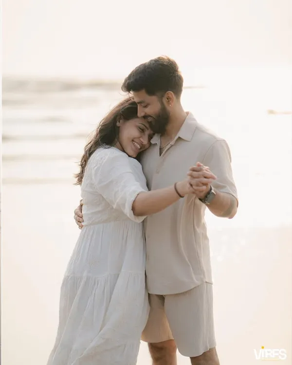 A couple shares a tender moment on the beach at sunset, dancing closely. The warm, golden light and her happy smile make this a perfect example of a romantic pre-wedding portrait.