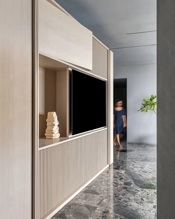 The kitchen block in 'A Wedged Haus' is designed as a monolithic object. Staggered woodwork accommodates utilities, while the light oak veneer finish allows it to stand as a sculptural element within the open-plan living space.