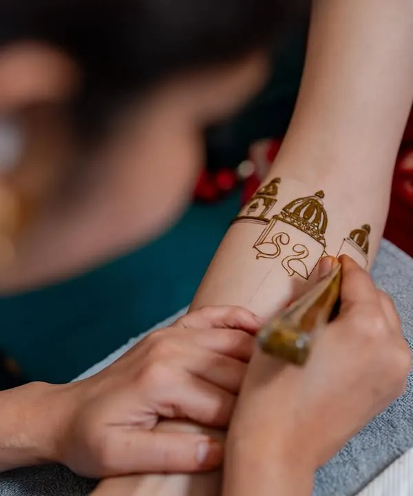 A close-up of the application process. Here, I am carefully drawing the domes of a palace motif on the bride's forearm, ensuring every line is perfect.