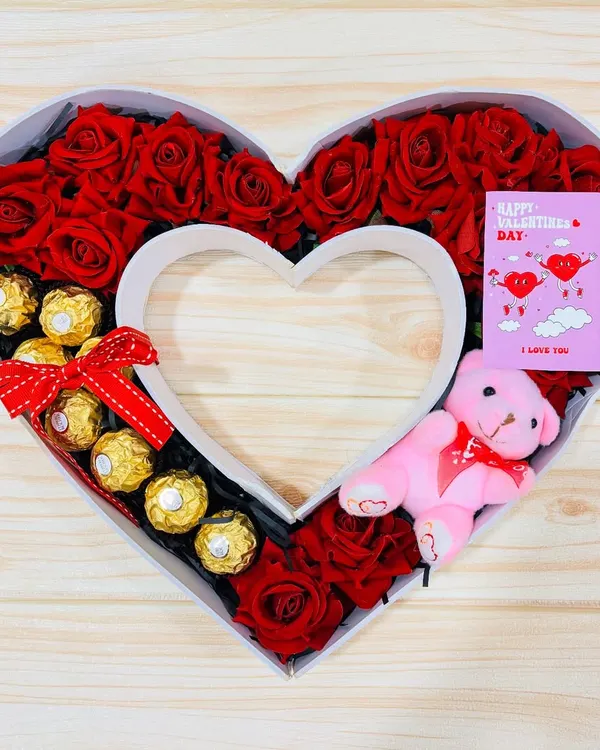 A hamper shaped like my heart. This monogram box is filled with red roses, Ferrero Rocher chocolates, a pink teddy bear, and a Valentine's card, making it a grand romantic gesture.