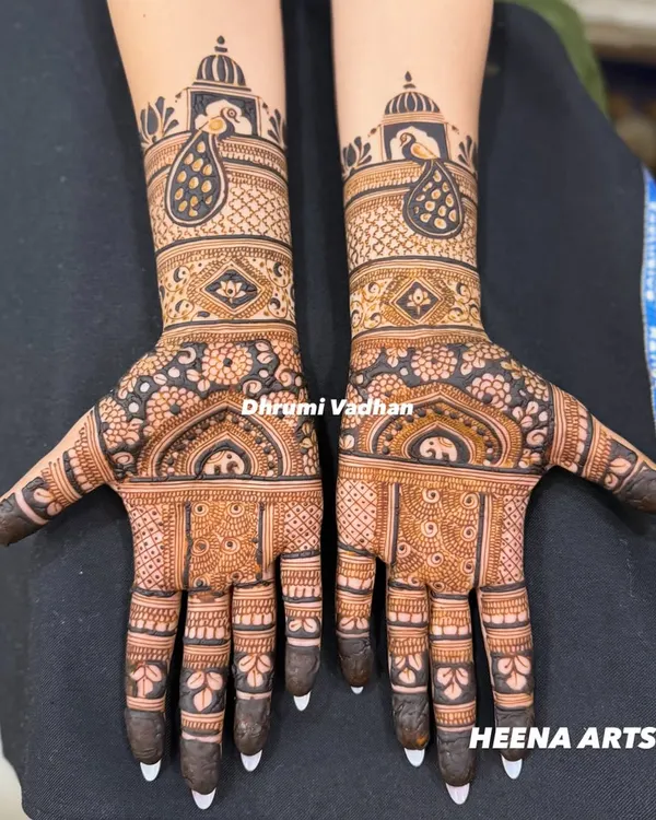 A classic Indian bridal mehendi featuring elegant peacocks and elephant motifs. The contrast between the delicate line work and the bold, filled-in elements makes the design pop.
