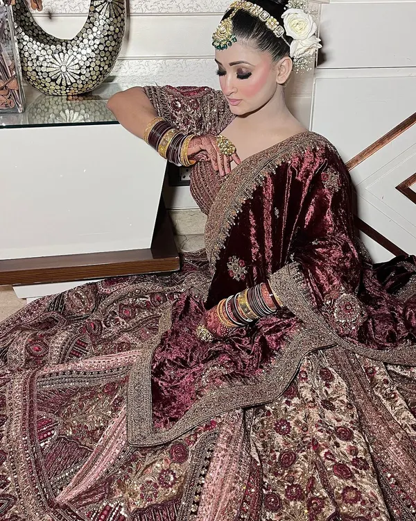 This deep maroon velvet lehenga is designed for a grand winter wedding. It features intricate all-over embroidery and is paired with a matching velvet dupatta for a truly royal bridal statement from head to toe.