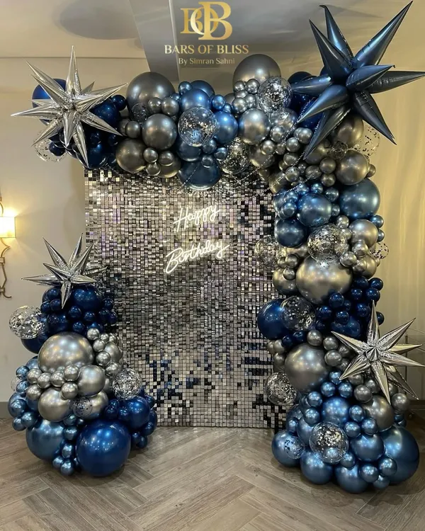 This is what a celebration should feel like. We created this glamorous birthday setup featuring a full silver sequin wall, a custom neon sign, and a dramatic chrome balloon arrangement in shades of blue and silver for a truly show-stopping effect.