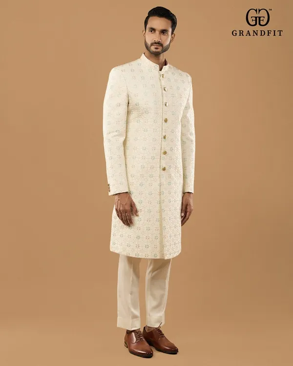 A side profile showcasing the flawless fit and drape of our custom sherwani. The delicate pastel embroidery adds a touch of modern refinement to this traditional garment for grooms.