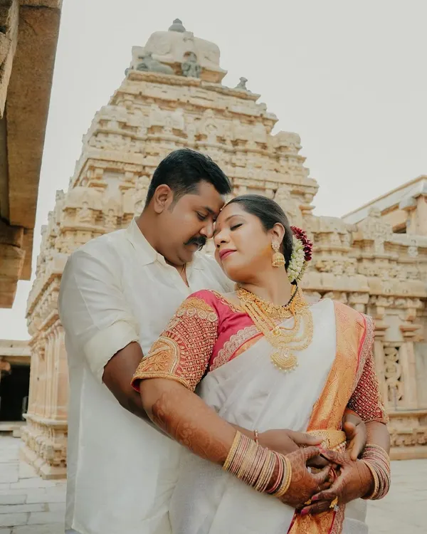 A beautiful, intimate portrait of a couple in traditional South Indian attire, set against the magnificent backdrop of a heritage temple. This shot perfectly blends cultural richness with romantic connection.