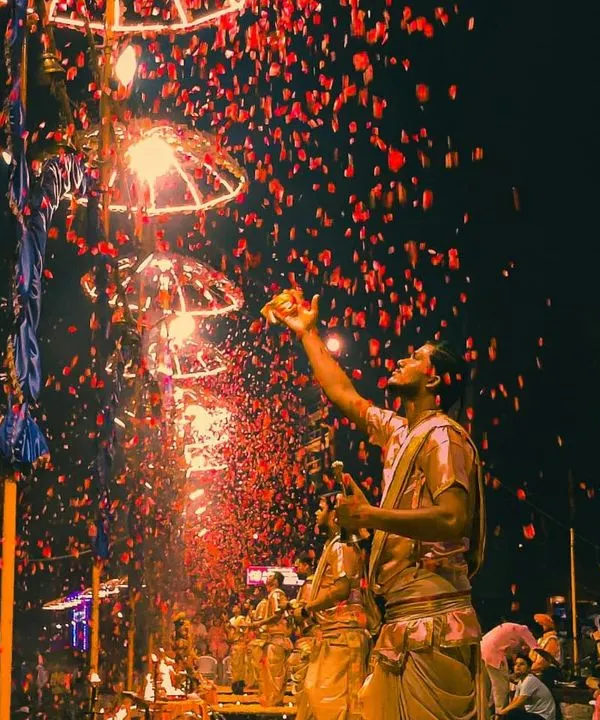 A priest showers flower petals during the grand Ganga Aarti on Dev Deepawali. This shot, with its vibrant colors and sense of motion, captures the celebratory essence of the ritual.