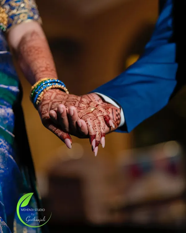 A beautiful moment captured between the bride and groom, showing a glimpse of their mehendi-adorned hands.