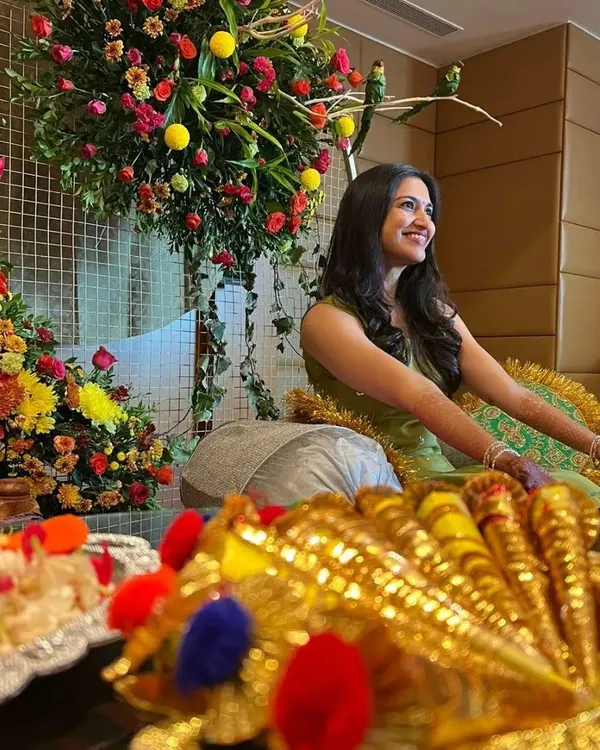 A happy client at her mehendi ceremony, surrounded by beautiful floral decorations. It's all about the festive vibes.