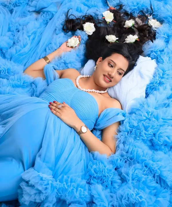 A dreamy, angelic portrait of the mom-to-be. Lying on a bed of the gown's blue tulle with white roses in her hair, this shot is pure elegance and serenity.