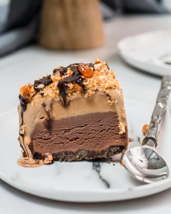 A perfect slice of our signature ice cream cake, revealing luscious layers of rich chocolate and nutty ice cream on a crunchy base. This is pure indulgence on a plate, a testament to 30 years of dessert magic.