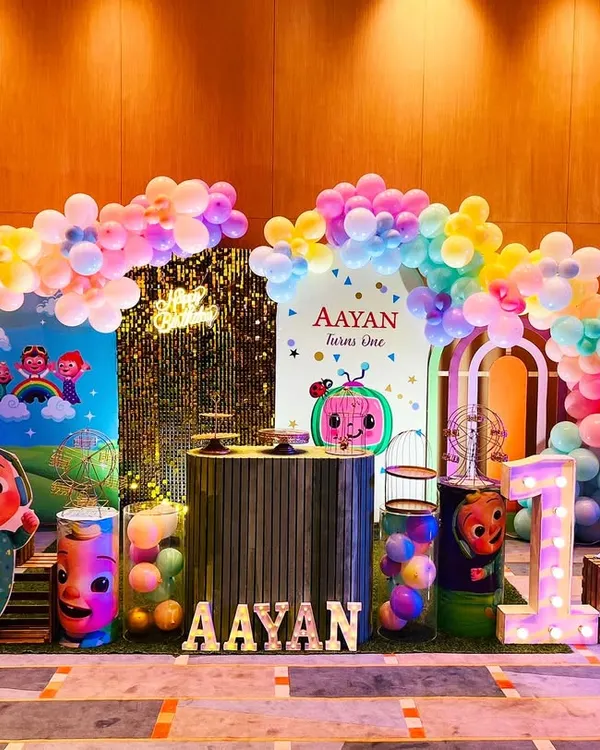 This Cocomelon-themed birthday party is full of color and fun. The setup includes a vibrant backdrop with all the characters, themed pedestals, and a light-up name sign for the birthday boy.