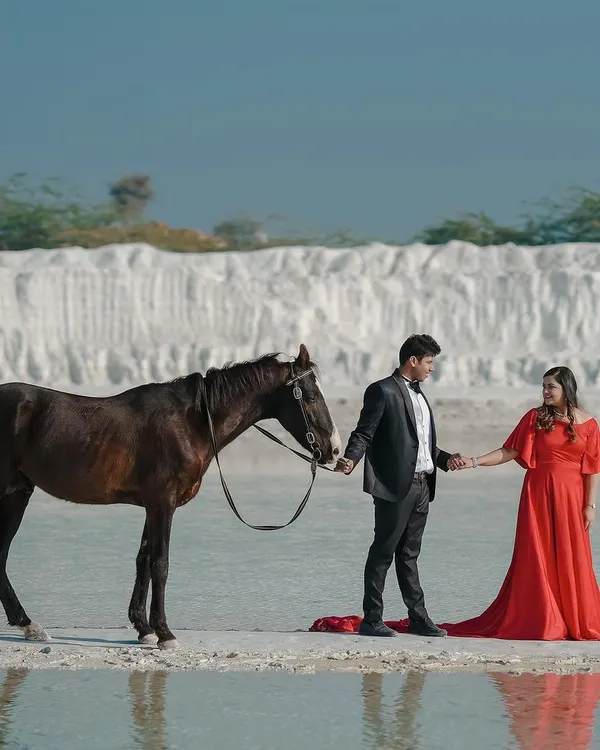 A truly magical pre-wedding shot featuring the couple with a majestic horse against a surreal white landscape. This kind of conceptual photography adds a fairytale element to your story.