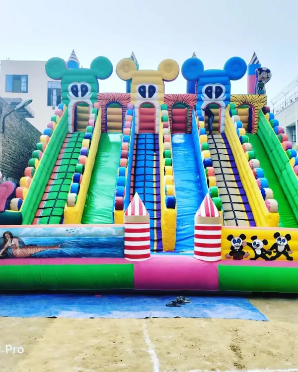 A massive 6-slider bouncy castle with a fun Mickey and clown theme, shown here ready for delivery. The multiple lanes are great for handling crowds at large fairs and amusement parks.