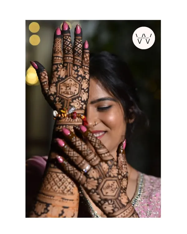 A happy client peeking through her beautifully hennaed hands.
