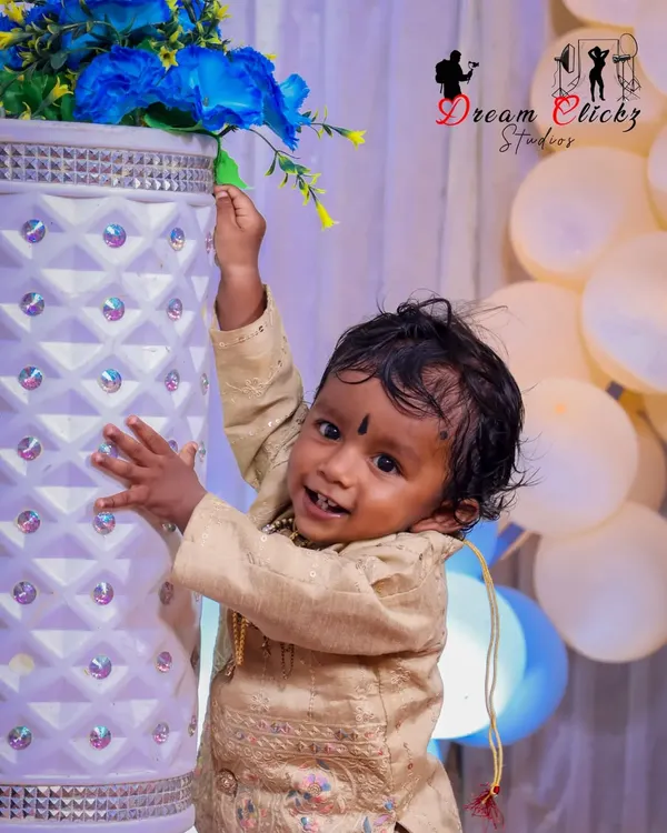 A happy baby boy enjoying his birthday photoshoot. His bright smile and curious hands reaching for the flowers show the playful energy I love to capture during these sessions.