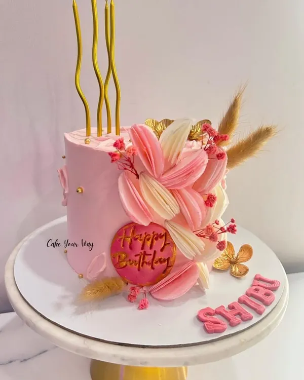 This cake is what dreams are made of. A tall, elegant pink cake with abstract floral details and delicate dried elements.