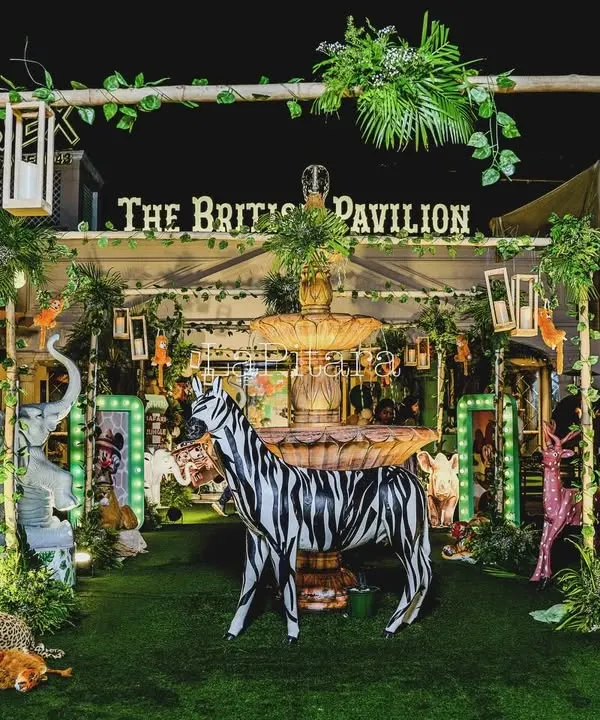 A full view of the Mickey Mouse jungle safari setup at The British Pavilion. The space is filled with life-sized animal props, illuminated character frames, and lush greenery, creating a truly wild and adventurous atmosphere.