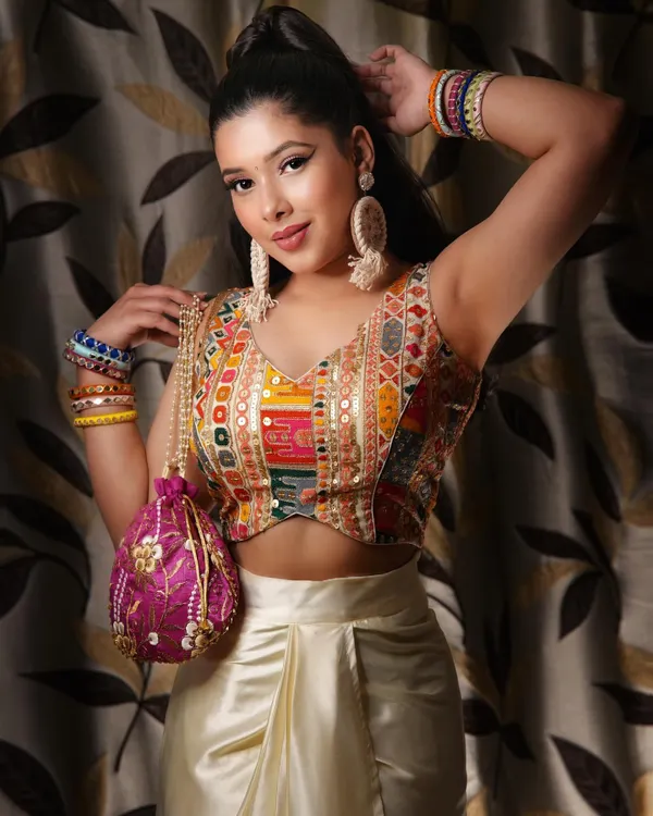 This is a modern take on festive wear, featuring a colorful embroidered blouse and a cream dhoti skirt. The look is completed with a potli bag and statement earrings, showing how to style a contemporary ethnic outfit.