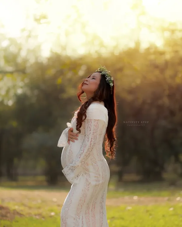 Soaking in the last rays of sun. This portrait in a white lace gown with a floral crown captures the pure, serene beauty of motherhood during the magical golden hour.