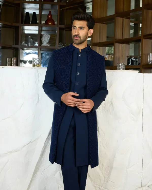 A full-length view of a layered Indo-Western look in deep navy. The textured, sleeveless long jacket over a matching kurta set creates a sophisticated and modern silhouette.