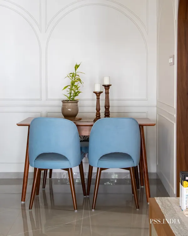 A simple yet elegant dining nook. The pop of color from the blue velvet chairs against the classic wall molding and warm wood table creates a charming space for intimate meals.