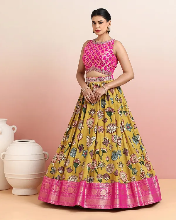 This vibrant mustard yellow lehenga with bold floral prints is a celebration of color and craft. The contrasting pink Bandhani-inspired blouse and rich zari border make it a perfect choice for a mehendi or sangeet ceremony.